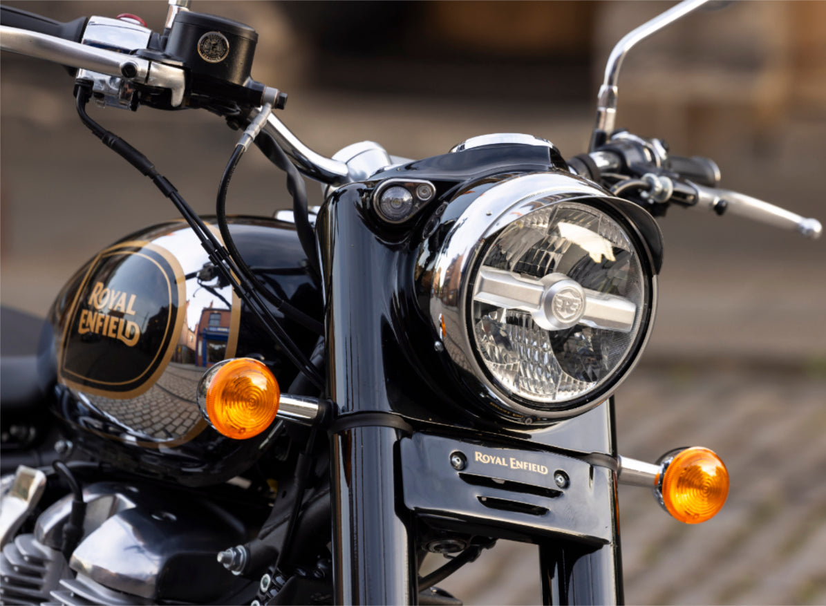 Close-up of a motorcycle Classic 650 headlight with 'Royal Enfield' branding.